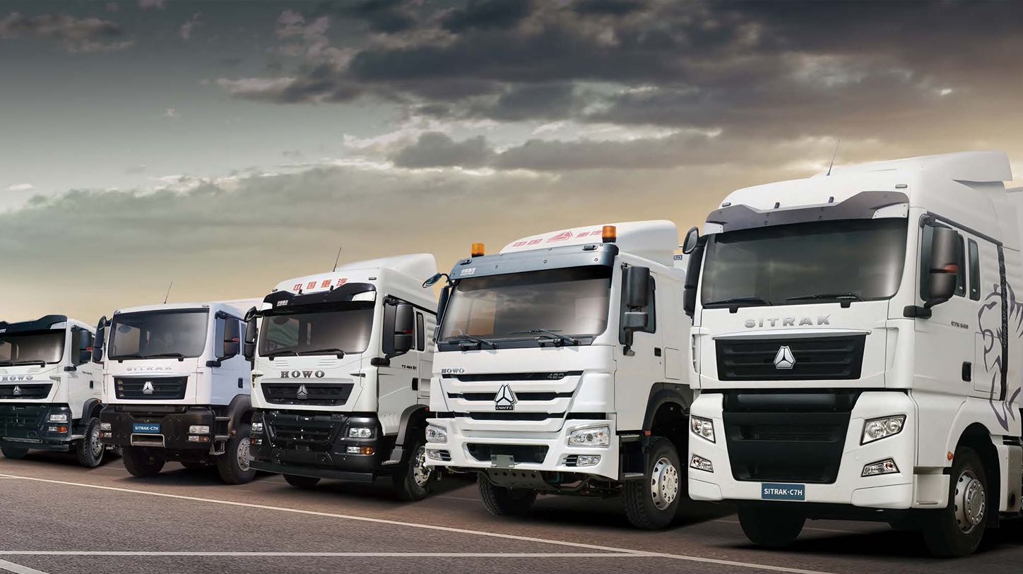 Camiões Sinotruck brancos da frota R&B alinhados no pátio industrial, representando a moderna infraestrutura de transporte e logística da empresa